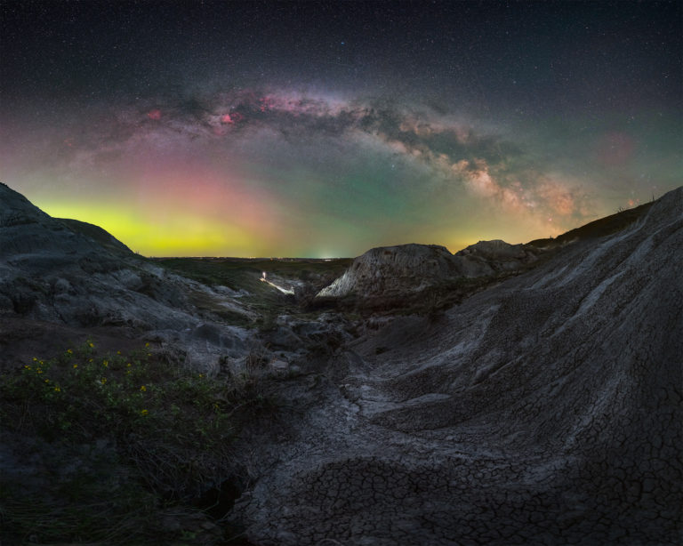 The milky way arch over badlands in saskatchewan with a portrait of a night photographer